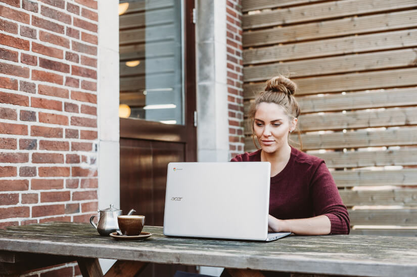 Woman using laptop outside cafe